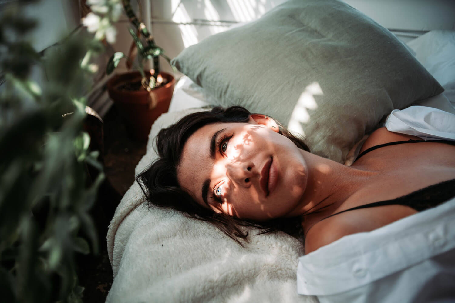 Woman beside a plant at a spa laying on bed